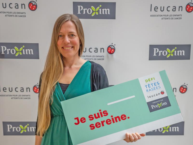 Valérie Vendette avant de se faire couper les cheveux pour le  Défi têtes rasées Leucan avec panneau Je suis sereine