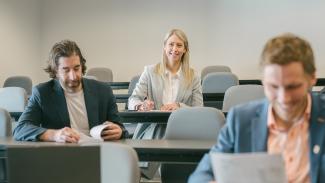 Femme souriante en classe à l'arrière-plan, deux hommes au travail à l'avant