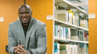 Chercheur souriant devant rangée de livres scientifiques