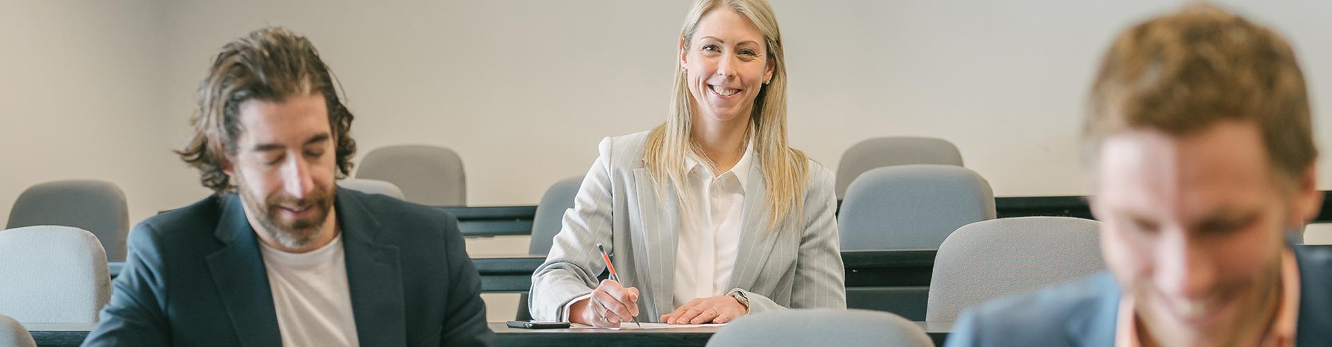 Femme souriante en classe à l'arrière-plan, deux hommes au travail à l'avant